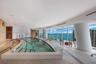 Indoor pool area featuring floor-to-ceiling windows, stone tile flooring, recessed ceiling lighting, and custom curved architectural columns