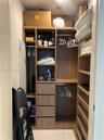 Custom closet organization system featuring wood-finish cabinetry, integrated shelving, four pull-out drawers, and dual hanging rods