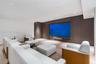 Custom media room featuring a large recessed television screen, built-in floor-to-ceiling paneling, light wood-finish flooring, and recessed ceiling l