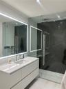 Wall-mounted floating vanity with integrated rectangular sink and stone-surface countertop, frameless glass-enclosed shower featuring large-format dar
