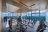 Fitness space featuring floor-to-ceiling windows, wood-paneled slat ceiling, rubberized flooring, and structural columns