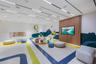 Open-concept room featuring a linear recessed lighting system, integrated ceiling speakers, and a wood-slat accent wall with a wall-mounted display