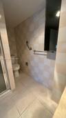 Bathroom featuring floor-to-ceiling checkerboard tile, large-format tile flooring, a glass-enclosed shower, and brushed metal hardware