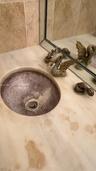 Countertop basin integrated into a stone vanity surface, complemented by decorative swan-motif faucet hardware and a large-format mirrored backsplash