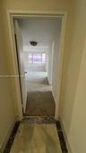 Interior foyer with stone flooring featuring decorative tile borders, carpeted flooring, and a multi-pane window