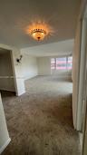 Interior space featuring wall-to-wall carpeting, an ornamental flush-mount chandelier, and a large multi-pane window