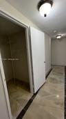 Hallway featuring stone tile flooring with decorative dark borders and flush-mount ceiling lighting, including a reach-in closet with built-in metal s