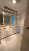 Bathroom featuring a large vanity with white cabinetry, integrated sink, and stone-surface countertop, complemented by floor-to-ceiling wall tiles and