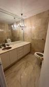 Bathroom featuring full-wall tile surround, vanity with inset sink and stone countertop, large-format tiled flooring, and a decorative crystal chandel