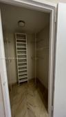 Walk-in storage featuring stone-finish flooring, built-in shelving unit, metal wire racking, and ceiling-mounted light fixture