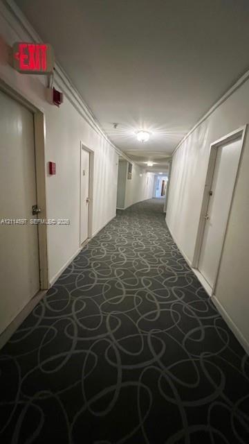 Interior hallway featuring patterned carpeting, recessed ceiling lighting, and solid-core doors