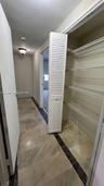 Storage closet with louvered bi-fold door, white wire shelving, and neutral tile flooring featuring dark stone-patterned accents