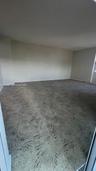 Spacious room featuring neutral wall paint and patterned carpeting