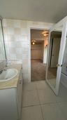 Bathroom featuring a vanity with an integrated basin, neutral stone-finish countertop, full-height wall tiling, and a door with an inset full-length m