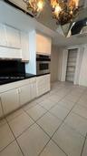 Kitchen featuring white cabinetry, dark countertops, built-in stainless steel double oven, tile flooring, and mirrored ceiling detailing