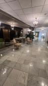 Large-format stone flooring, wall-spanning mirror, and multi-arm chandelier fixtures in a high-ceiling lobby