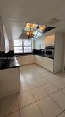 Kitchen featuring light-toned cabinetry, contrasting dark countertops, built-in wall oven, tiled flooring, and a mirrored ceiling element with integra