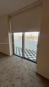 Sliding glass door with integrated roller shade, leading to a private balcony featuring a checkered tile floor and metal railing