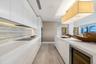 Kitchen featuring high-gloss cabinetry, stone-finish backsplash with integrated under-cabinet lighting, solid-surface countertops, wood-finish floorin