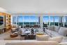 Living area featuring expansive floor-to-ceiling windows, integrated wall cabinetry with recessed shelving, and wood-finish flooring