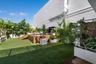 Rooftop terrace featuring artificial turf, a wood-slat deck, built-in planters, and perimeter landscaping