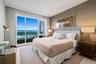 Floor-to-ceiling windows, private balcony access, neutral textured wall covering, and recessed lighting