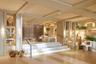 Multi-level interior space featuring coffered ceilings, light-toned wood paneling, recessed lighting, integrated wall shelving, and a tiered staircase