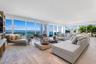 Expansive living space featuring floor-to-ceiling glass windows, wood-finish flooring, recessed lighting, and a built-in media shelving unit