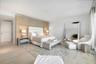 Light-toned wood-finish flooring, custom built-in wood-panel headboard with integrated lighting, and recessed ceiling lighting