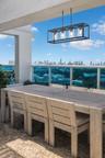 Covered balcony featuring natural stone flooring, a matte black rectangular four-light pendant fixture, and a metal railing