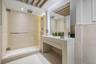 Stone-tiled shower featuring a frameless glass enclosure and rainfall showerhead, complemented by a custom stone vanity with an integrated sink and re