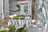 Expansive interior featuring large-format stone wall cladding, custom sculpted organic wood pillar, recessed floor accent lighting, and dual conical p
