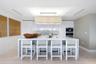 Kitchen featuring high-gloss cabinetry, stone-finish island waterfall countertop, integrated stainless steel appliances, and rectangular pendant light