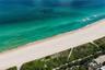 Direct oceanfront access featuring expansive sandy shoreline, turquoise water, and native coastal vegetation