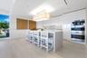 Modern kitchen featuring a waterfall-edge island, high-gloss flat-panel cabinetry, integrated stainless steel appliances, and wood-finish flooring