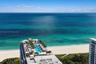 Elevated oceanfront terrace featuring an expansive lap pool, integrated palm tree landscaping, and paved sun deck surfaces