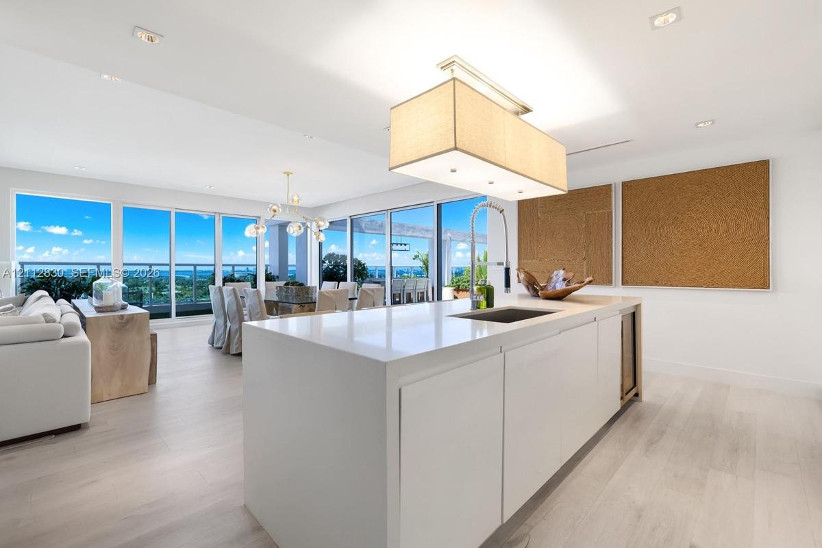 Kitchen island with stone-finish countertop, integrated sink, and built-in under-counter beverage chiller, complemented by wood-finish flooring, reces