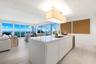 Kitchen island with stone-finish countertop, integrated sink, and built-in under-counter beverage chiller, complemented by wood-finish flooring, reces