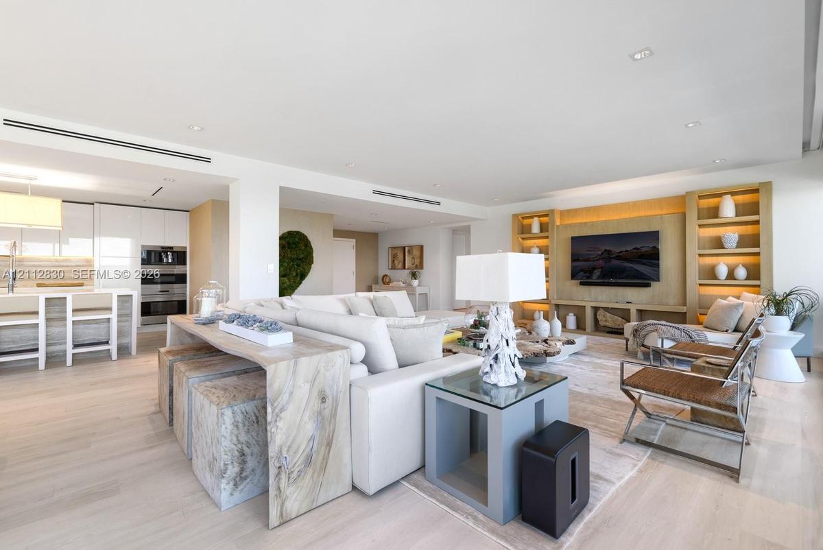 Open-concept space featuring wood-finish flooring, recessed lighting, and custom wood built-in shelving with integrated lighting
