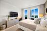 Bedroom featuring wood-finish flooring, built-in desk cabinetry, floor-to-ceiling windows, and balcony access