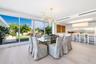 Floor-to-ceiling sliding glass panels, wood-finish flooring, linear recessed lighting, brass-finish multi-arm chandelier, and white flat-panel cabinet