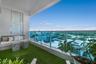 Covered balcony featuring synthetic turf flooring and a glass railing with metal framing