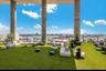 Expansive outdoor terrace featuring synthetic turf flooring, floor-to-ceiling structural concrete columns, and a perimeter metal railing