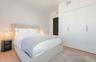 Room featuring smooth-finish white walls, light-toned wood-finish flooring, and built-in floor-to-ceiling storage cabinetry with vertical metallic har