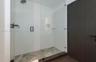Walk-in shower featuring a frameless glass enclosure, white subway tile surround, hexagonal tile flooring, matte black rainfall showerhead, and integr
