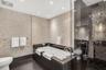 Bathroom featuring pebble-textured stone accent walls, a jetted soaking tub with a dark stone surround, a glass-enclosed shower with diamond-patterned