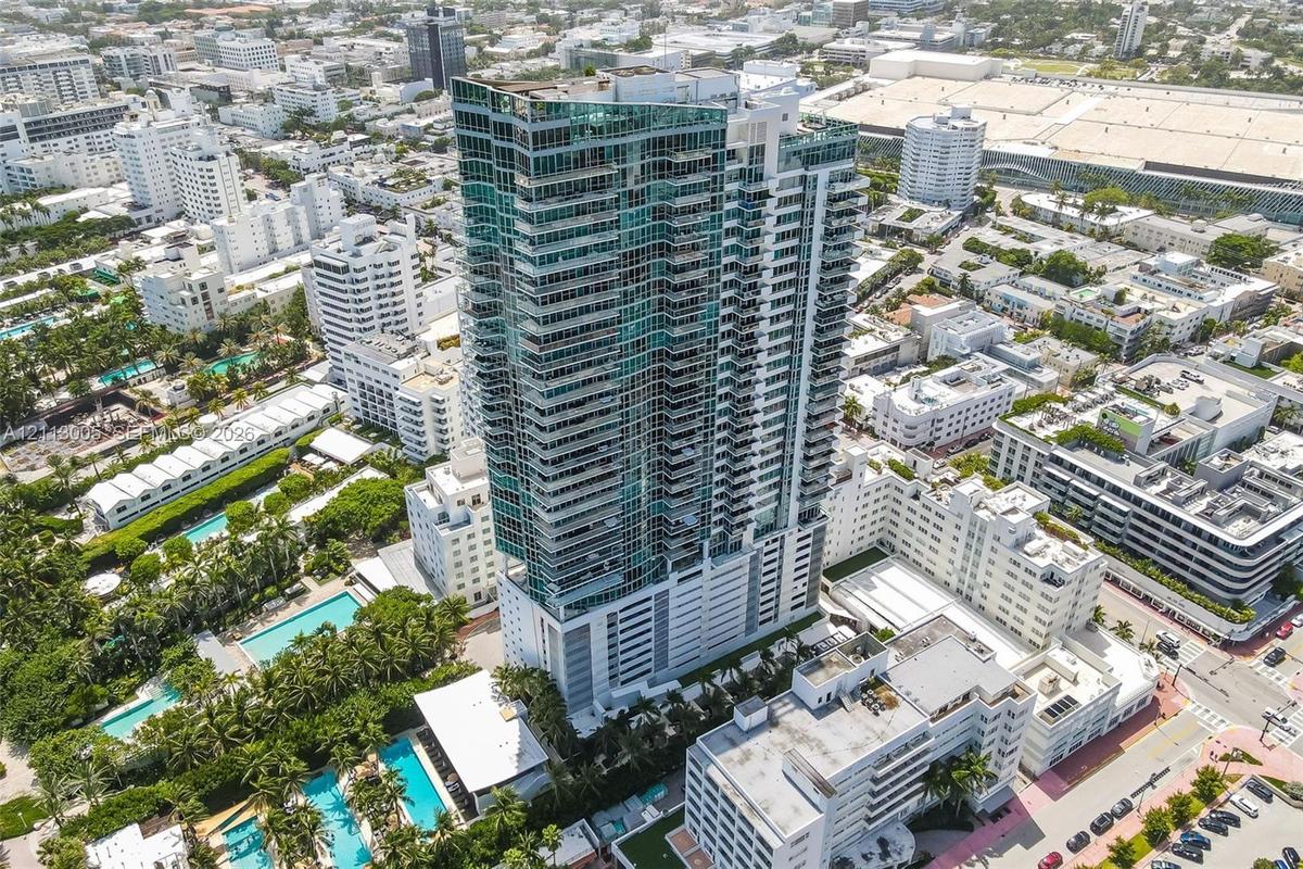 High-rise tower featuring glass facade construction, external balconies, and multi-level parking podium