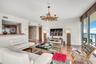 Living area featuring wood-finish flooring, a textured stone feature wall, a custom driftwood-style chandelier, and floor-to-ceiling windows with balc