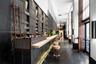 Custom bar area featuring full-height floor-to-ceiling display shelving with a rolling ladder, stone countertop, intricate metalwork detailing, and te