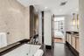 Bathroom featuring a deep soaking jetted tub, pebble-textured wall tiling, dark stone vanity countertop, slate tile flooring, and integrated pendant l